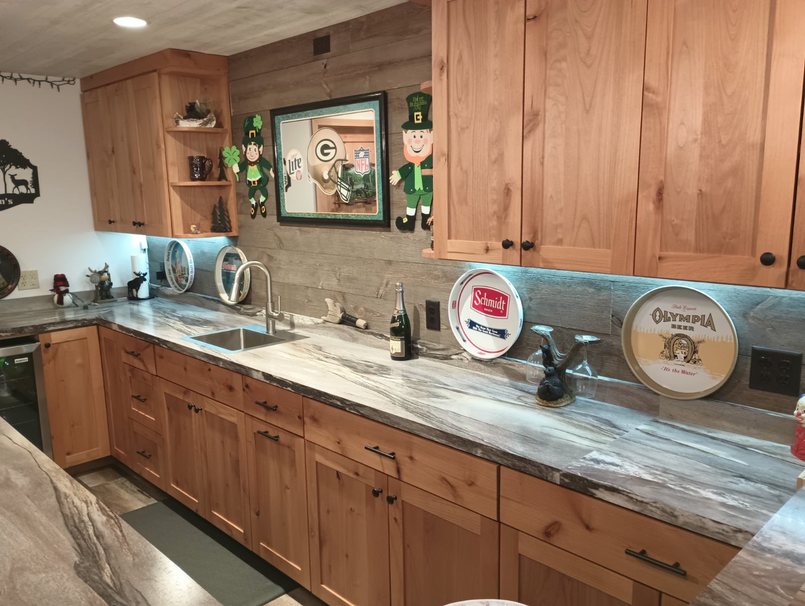 Custom wood cabinets with under-cabinet lighting and stone-look countertop in a basement bar