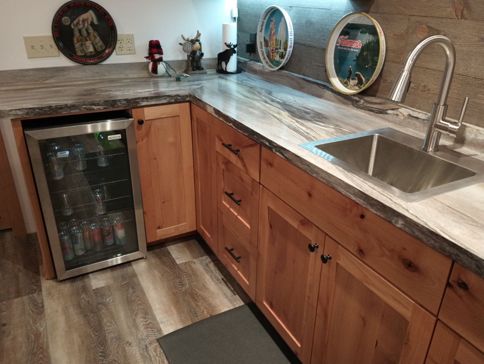 Custom cabinets with built-in beverage fridge and sink in a basement bar