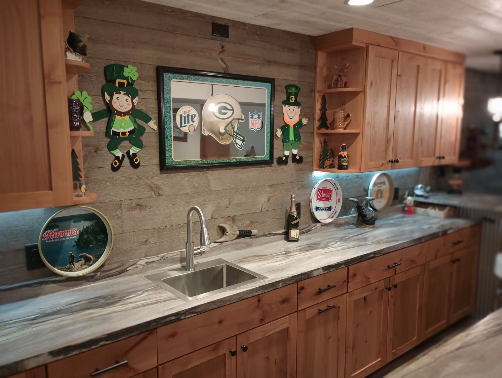 Custom shaker-style cabinets with sink and weathered wood backsplash in a basement bar